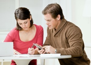 Determined couple using calculator to pay monthly bills